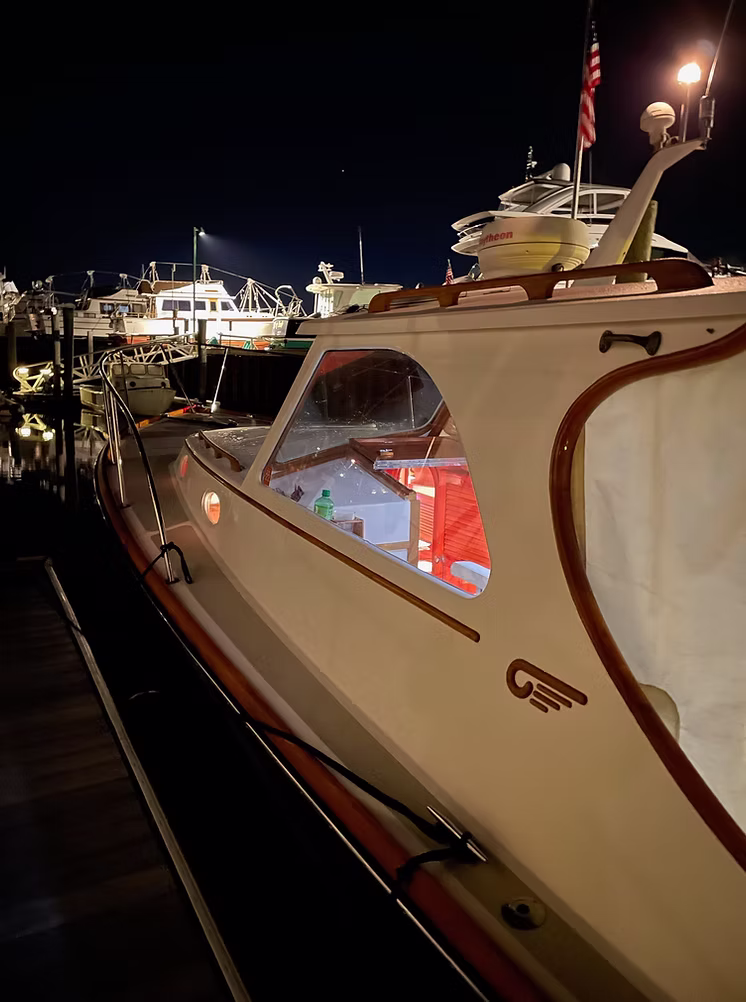 The boat tied up at the dock at night, cabin light glowing